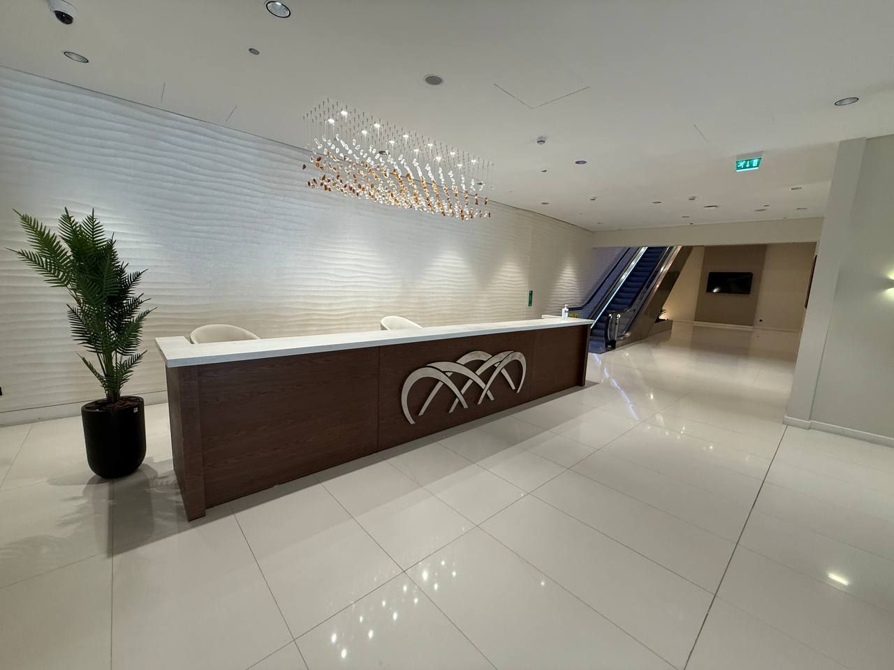 The reception desk beneath the crystal chandelier, with the escalator behind