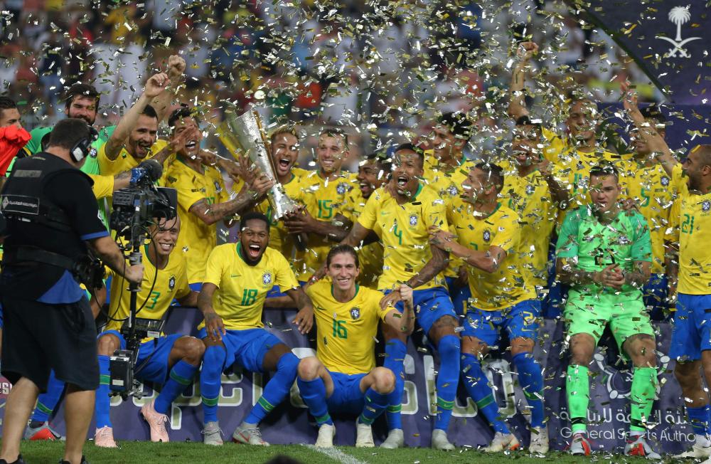 The Brazil squad celebrate with the trophy under a shower of confetti on the pitch